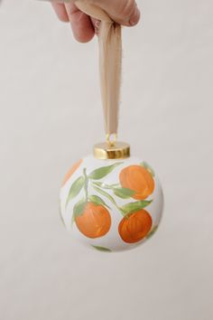 an ornament with oranges painted on it being held by someone's hand