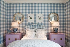 a blue and white checkered wall with two lamps on either side of the bed