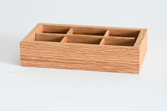 a wooden box with compartments for pens and pencils on a white surface, top view