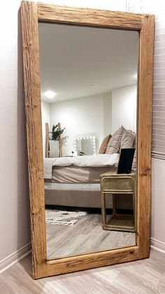 a mirror sitting on top of a wooden floor next to a bed