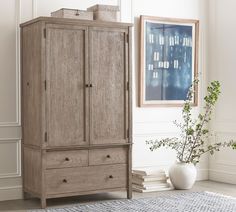 a wooden armoire in a room next to a vase and painting on the wall