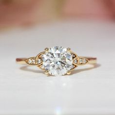 a close up view of a ring with a white diamond in the center, on a table