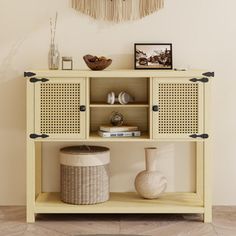 a white shelf with baskets and vases on it in front of a wall hanging