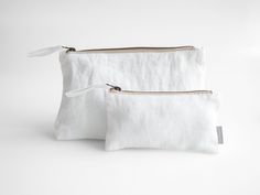 two white linen pouches with zippers on each side, one is open and the other has a zip