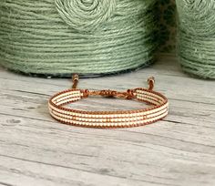 a close up of a bracelet on a wooden surface with yarn in the back ground