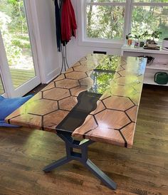 a wooden table sitting on top of a hard wood floor next to a large window