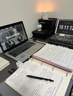 an open laptop computer sitting on top of a desk next to a notebook and pen