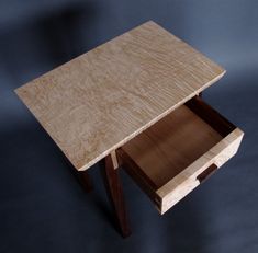 a small wooden table with two drawers on it's sides and one drawer open