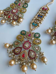 These gorgeous sets of tikka and jhumka come in 2 beautiful colors and are pastel tones to match any outfit. The multi set is a subtle mix of colors to create a uniform look and the champagne is the perfect single pop of color for any outfit! Comes as a set of earrings and headpiece (tikka) Elegant Multicolor Sets With Latkans, Elegant Multicolor Jhumkas For Festive Occasions, Multicolor Fusion Sets For Weddings, Multicolor Fusion Style Wedding Sets, Multicolor Fusion Wedding Sets, Elegant Multicolor Kundan Jhumkas, Multicolor Kundan Sets With Latkans, Elegant Multicolor Chandbalis With Latkans, Multicolor Fusion Chandbalis For Celebrations