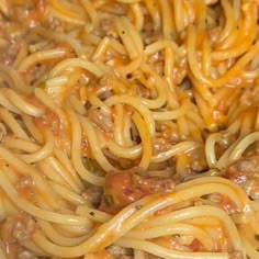 some noodles are being cooked in a pan with meat and cheese on top, ready to be eaten