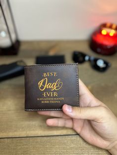 "Best Dad Ever Leather Wallet With Children Names, Father's Day Gift, Custom Leather Engraved Wallet, Wallet For Men, Personalized Gift ✦Do you need a high-quality, protective wallet that will hold your valuables in a secure and stylish way? You have come to the right place! ✦Our wallets are made from the finest vegetable-tanned full-grain leather. The perks of having the wallet made from premium quality full-grain leather makes the wallet age backward; the color becomes more vibrant and pretty. ✦Alongside its durability, our wallets are built-in with RFID blocking to protect your identity so that it doesn't go into the wrong hands. ✦Add a personal touch to this wonderful wallet by engraving and adding a quote to the side of your choice! ✦This wallet is a perfect present for Your Loved One Father's Day Gift Wallets With Coin Pocket, Father's Day Wallets With Coin Pocket, Father's Day Gift Wallet With Coin Pocket, Father's Day Rectangular Wallets With Card Slots, Personalized Brown Trifold Wallet For Father's Day, Brown Wallets For Father's Day, Rectangular Wallets With Interior Card Slots For Father's Day, Brown Wallet For Father's Day, Personalized Brown Wallets For Father's Day