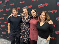 three people standing next to each other in front of a red carpeted wall with the words comic con on it