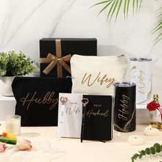 a table topped with black and white boxes filled with personalized items, flowers and candles