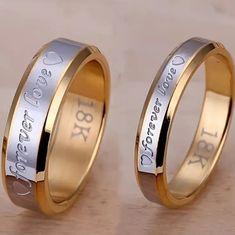 two gold and silver wedding rings with names engraved on the sides, one is for each other