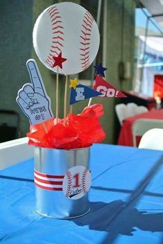 a baseball themed centerpiece in a bucket on top of a blue cloth covered table