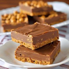 three pieces of chocolate peanut butter bars stacked on top of each other in white plates