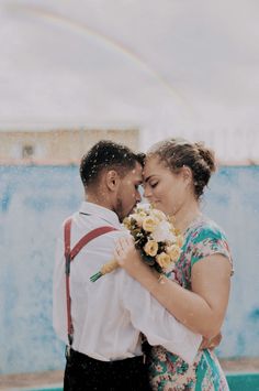 a man and woman standing next to each other in front of a blue wall with a rainbow