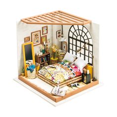 a doll house with a bed, desk and pictures on the wall in it's corner