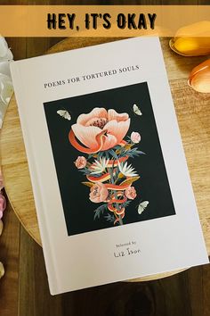 an open book sitting on top of a wooden table next to some flowers and leaves