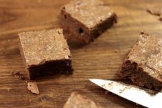 brownies cut into squares on a wooden table with a knife