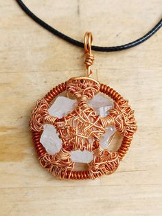 a copper wire and glass pendant sitting on top of a wooden table