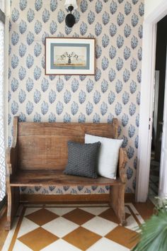 a wooden bench sitting in the middle of a room next to a door and window