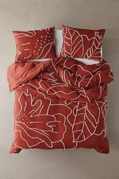 an orange and white comforter set with two pillows on the bottom, and one pillow in the middle