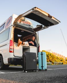 a man sitting in the back of a van with luggage