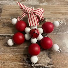 an ornament made out of red and white balls on a wooden table with a bow