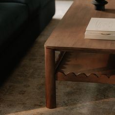 a coffee table with a book on it and a couch in the backround