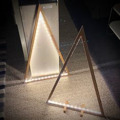 two triangle shaped mirrors sitting on the floor in front of a counter top with lights