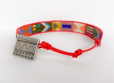 a red string bracelet with a silver metal clasp and bead work on the clasp