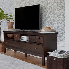 a flat screen tv sitting on top of a wooden entertainment center next to a potted plant