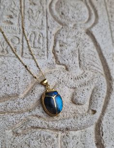 This amazing pendant will make you feel like a living goddess Hand-carved scarab, an ancient reproduction, inlaid with a genuine deep blue shimmering labradorite stone. The gem fits perfectly in the gaps of the beetle. A beautiful tribute to ancient Egypt and to the divine archetypes that we incarnate. In ancient Egypt, the fascinating Scarab Beetle was associated with the solar cycle, as a concept of rebirth and regeneration. The God Khepri was rising the sun every day before rolling it above the horizon, then carried it through the other world after sunset, just to renew it, again, the next morning. The decisive symbolism came from the association of the dung ball to the sun: the scarab rolling his dung ball provided an explanation of the sun's movement in the sky. Powerful amulet used a Artisan Ankh Jewelry For Gift, Beetle Jewelry, Scarab Jewelry, Egyptian Inspired Jewelry, Egypt Jewelry, Ancient Egyptian Jewelry, The Beetle, Egyptian Scarab, Scarab Beetle