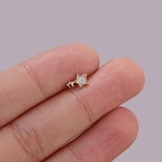 a person's hand holding a tiny star shaped diamond ring in their left hand