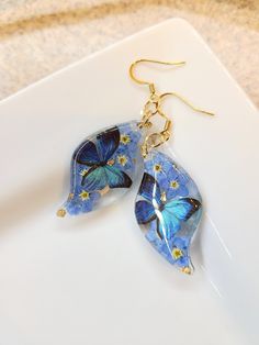 How darling are these Real Flower earrings! Perfect for yourself or for your loved ones.  The Dangles are made with real pressed forget me not flowers and Cerulean Butterflies with a hint of gold flakes.  All Jewelry findings are Nickel and Lead Free. The petals and ferns have been carefully preserved to retain their color and would make a great gift for your loved ones. This piece was made with real flowers and hence it is important to preserve the jewelry in the box provided safely away from direct sunlight.  You can see more of my Handmade Items here:  https://www.etsy.com/shop/Thecraftiechristie Whimsical Blue Flower Earrings For Gift, Blue Whimsical Earrings For Gifts, Teardrop Flower Earrings Gift, Nature-inspired Teardrop Earrings For Gifts, Teardrop Flower Pierced Earrings Gift, Nature-inspired Jewelry Ear Wire For Gift, Handmade Whimsical Teardrop Jewelry, Whimsical Handmade Teardrop Jewelry, Whimsical Earrings For Mother's Day Gift