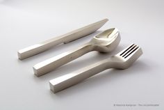 three forks and two knives sitting next to each other on a white counter top,