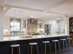 a kitchen with an island and bar stools next to the stove top oven in it