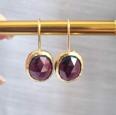 These red, oval solid gold Garnet earrings were made in a classic and chic design to create your go-to earrings for days and nights. These gold red gemstone earrings were 100% handmade and are a perfect gift for those celebrating their birthdays in January. Garnet is the official January birthstone and shines beautifully in the gold setting in a deep wine-red color. It brings abundance, prosperity, and success. It builds self-confidence, inspiration, and creativity, and increases commitment, hon Drop Gold Earrings, Birthday Earrings, Red Garnet Earrings, Custom Signet Ring, Simple Gold Earrings, Gold Pinky Ring, Signet Rings Women, January Birthday, Signet Ring Men