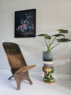 a wooden chair sitting next to a potted plant on top of a white table