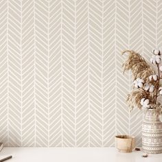 a vase with cotton in it next to a wallpapered background that looks like herringbones