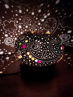 an intricately designed lamp is lit up on a table with polka dots and circles