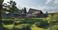 the house is surrounded by tall grass and trees, with purple flowers in the foreground