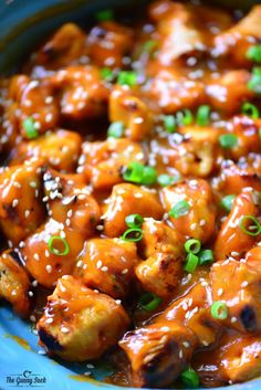 chicken with sesame seeds and green onions in a blue bowl