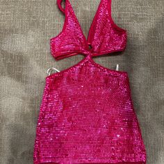 a pink top with sequins is laying on the ground next to a pair of scissors