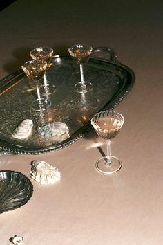 a tray with some wine glasses on top of it and other glassware around it