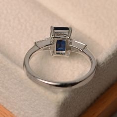 This ring features a 6*8mm emerald cut lab sapphire and sterling silver finished with rhodium. Customization is available. It is made by hand, and it will take about 7 days to finish the ring after your payment is completed. Main stone: Lab sapphire Main stone weight: Approx 1.90 ct Metal type: sterling silver finished with rhodium Accent stone: cz Customization is available, I also can make it with 14k solid gold (white or yellow or rose) and diamond accent stone, just feel free to contact me. Rectangular Lab-created Sapphire Ring For Anniversary, Anniversary Rectangular Lab-created Sapphire Ring, Elegant Sapphire Ring With Emerald Cut, Rectangular Sapphire Anniversary Ring, Sapphire Rectangular Promise Ring, Elegant Rectangular Lab-created Sapphire Rings, Rectangular Sapphire Promise Ring In Sterling Silver, Radiant Cut Sapphire Promise Ring, Emerald-cut Sapphire Birthstone Ring