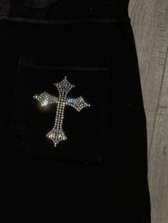 a cross is on the pocket of a pair of black pants with sequins