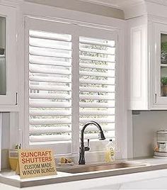 a kitchen with white cabinets and windows covered in blinds that look like they are closed