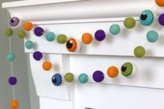 an image of a garland made out of felt balls and eyeballs hanging from the side of a window